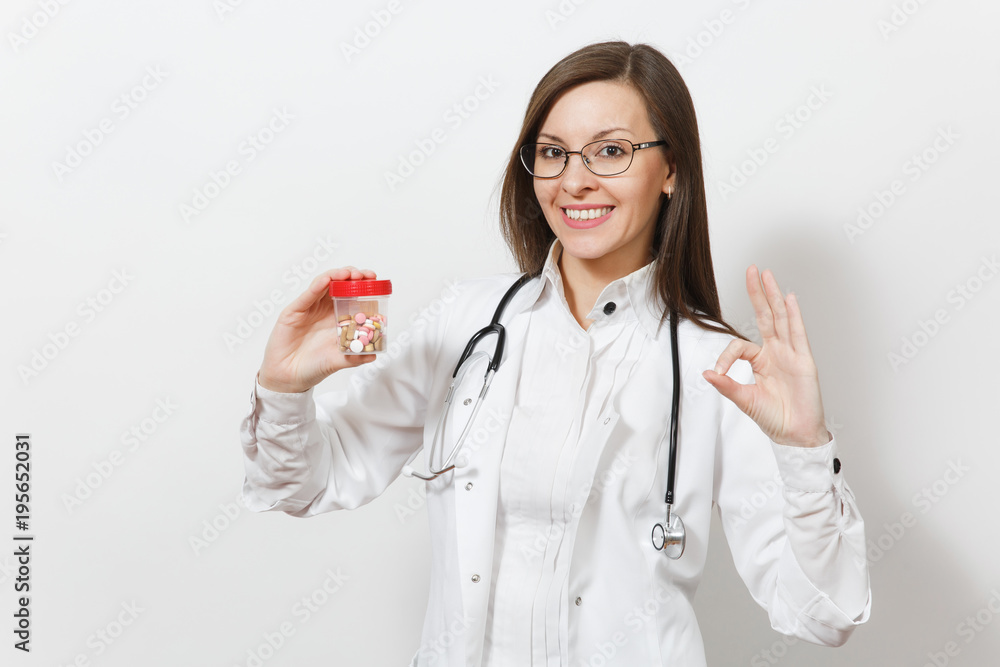 Smiling beautiful doctor woman with stethoscope, glasses showing OK gesture isolated on white background. Female doctor in medical gown holds bottle with pills. Healthcare personnel, medicine concept. Smiling beautiful doctor woman with stethoscope, glasses showing OK gesture isolated on white background. Female doctor in medical gown holds bottle with pills. Healthcare personnel, medicine concept.