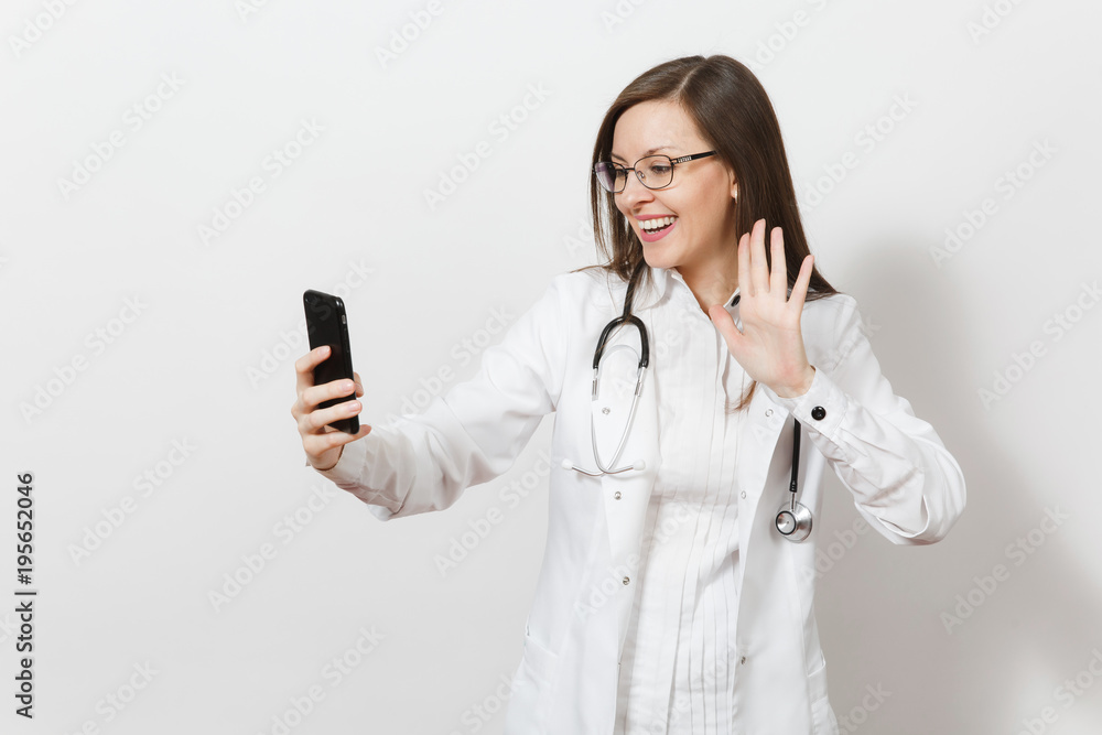 Smiling fun beautiful young doctor woman with stethoscope, glasses isolated on white background. Female doctor in medical gown doing selfie on mobile phone. Healthcare personnel, health, medicine Smiling fun beautiful young doctor woman with stethoscope, glasses isolated on white background. Female doctor in medical gown doing selfie on mobile phone. Healthcare personnel, health, medicine