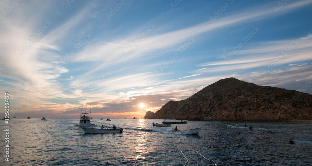 Fototapeta premium Fishermans sunrise view of fishing boat going out for the day past Lands End in Cabo San Lucas in Baja Mexico