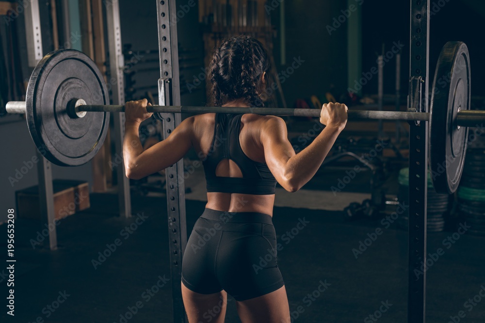 Fit woman lifting the barbell in the gym Fit woman lifting the barbell in the gym