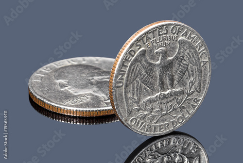 Quarter dollar coins on dark mirror surface