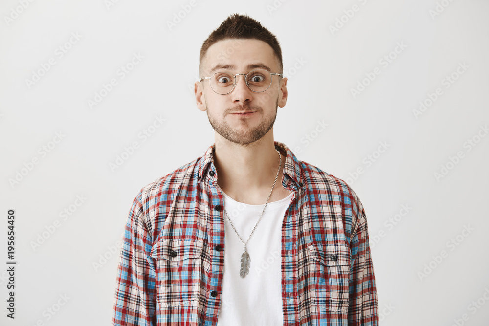 Funny confused caucasian student in glasses, smiling weirdly and staring with popped eyes as if being in awkward situation. Boyfriend came to dinner with girlfriend but met his ex. Emotions concept Funny confused caucasian student in glasses, smiling weirdly and staring with popped eyes as if being in awkward situation. Boyfriend came to dinner with girlfriend but met his ex. Emotions concept