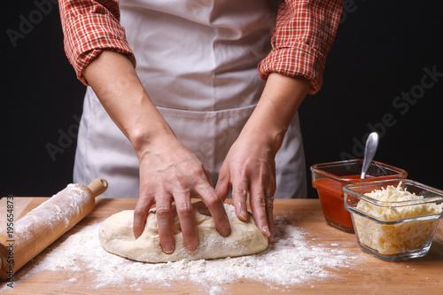 Woman kneads pizza dough.