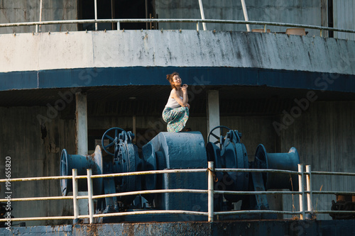 Young beautiful mixed race woman stands on an abandoned giant ship.