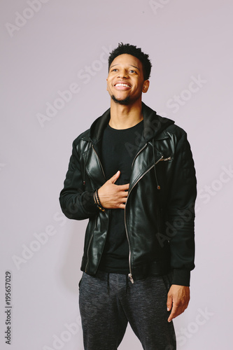 Cool young man in black leather jacket, isolated on grey background