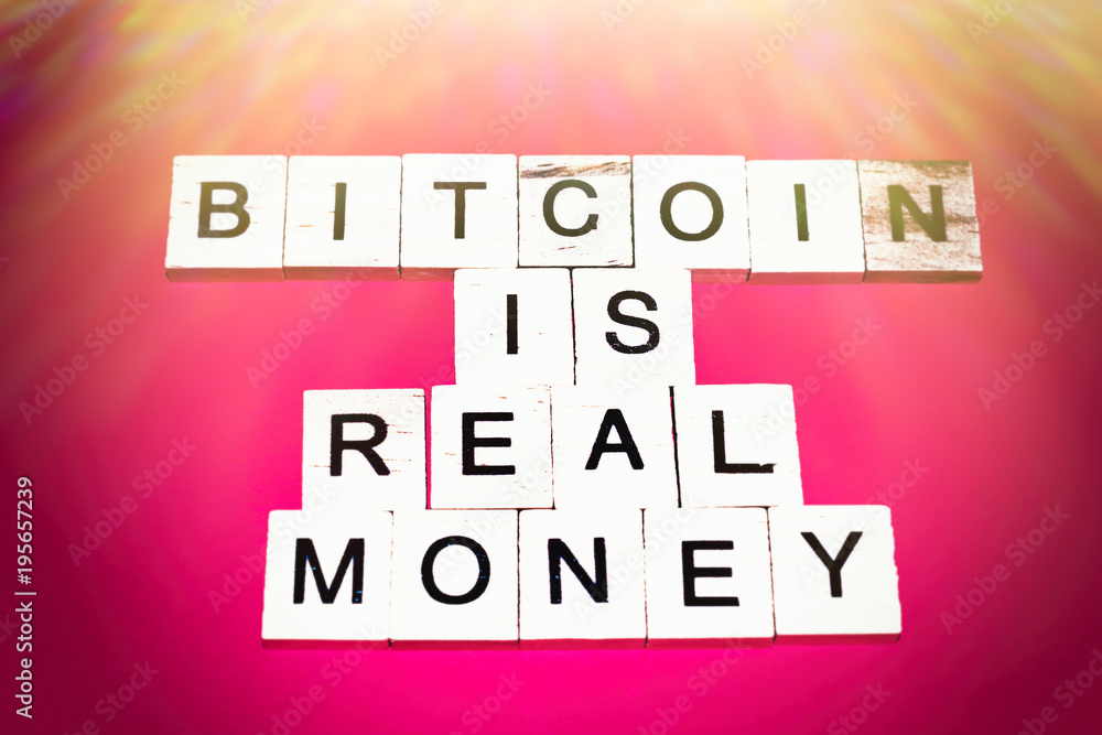 Wooden blocks on a red background spelling words Bitcoin is real money Wooden blocks on a red background spelling words Bitcoin is real money