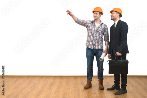 The two happy engineers gesture on the white wall background