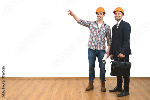 The two men in helmets gesture on the white wall background