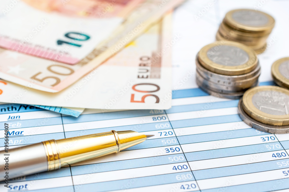 Euro bills and coins with pen on the financial graphs. Business concept. Euro bills and coins with pen on the financial graphs. Business concept.