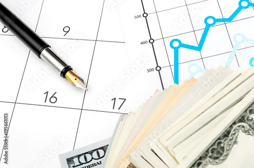 Business concept. Financial graphs with money and pen on calendar.