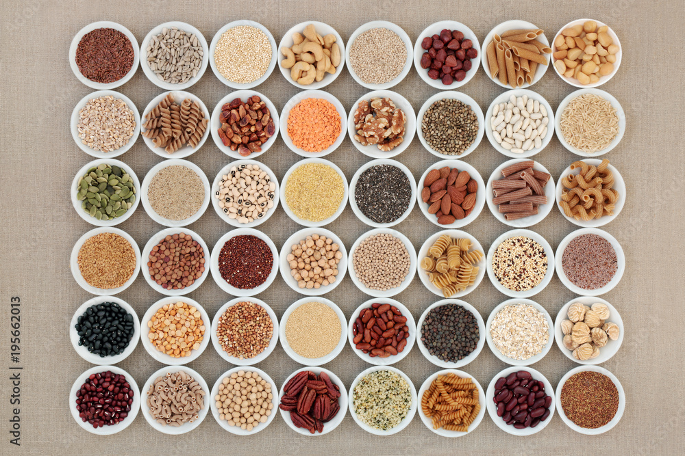 Vegan high protein dried super food selection with nuts, seeds, legumes, cereals and grains. Health foods high in fibre, antioxidants, anthocyanins, minerals and vitamins. On hessian, top view.