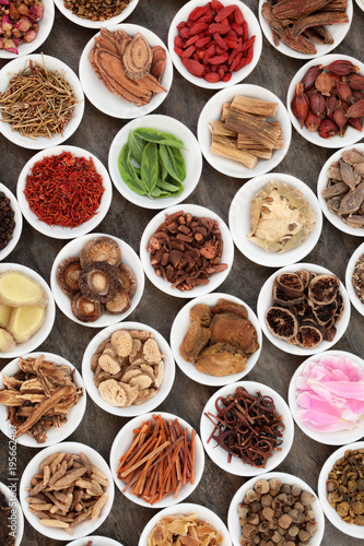 Chinese herbal medicine with traditional herbs in white porcelain bowls on marble background. Top view.