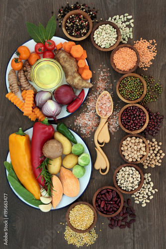Health food concept with fresh vegetables, pulses, herbs, spice, himalayan salt and olive oil with foods high in vitamins, minerals, smart carbs, anthocyanins, antioxidants and fibre, top view on oak.
