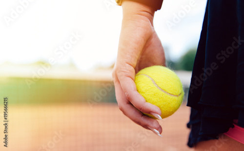 Woman holding tennis ball standing on the court. Close-up view. © Maksym Azovtsev