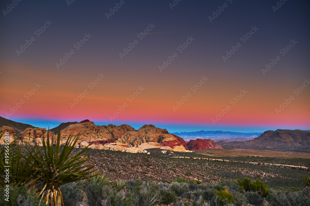 sun setting over redrock canyon rocks with las vegas in background
