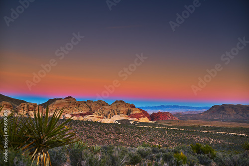 sun setting over redrock canyon rocks with las vegas in background