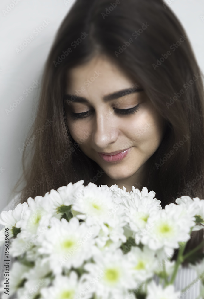 A beautiful girl with black hair looks at a bouquet of white flowers. A young woman received flowers from her beloved. A beautiful girl with black hair looks at a bouquet of white flowers. A young woman received flowers from her beloved.