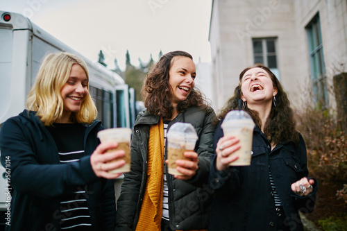 young girls holding cups of coffee drinks while laughing together