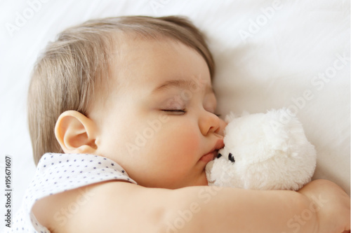 Photography Sweet little baby sleeping and hugging white teddy bear, close-up