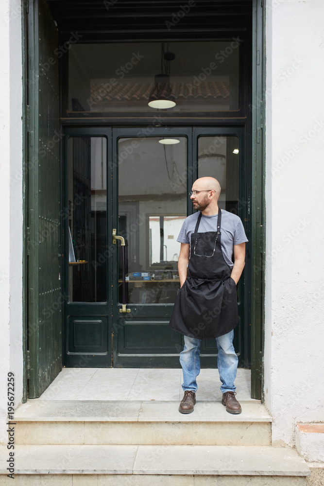 Portrait of an artisan standing in front of the workshop entrance Portrait of an artisan standing in front of the workshop entrance