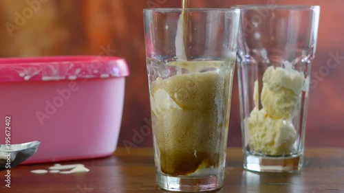 Preparing black cow cola ice cream soda floats against rustic wood background.