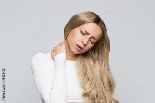 Closeup studio portrait of unhealthy woman with pain in her neck and back, isolated on gray background. Cervical arthritis, osteochondrosis, diseases of the musculoskeletal system concept 