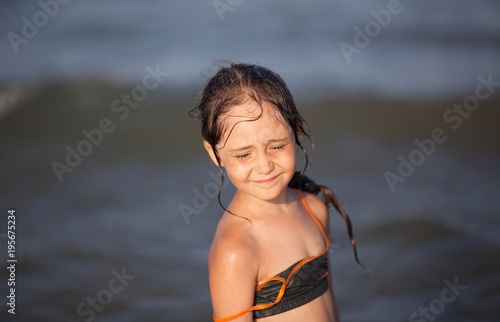 Little girl in bikini plays in the sea