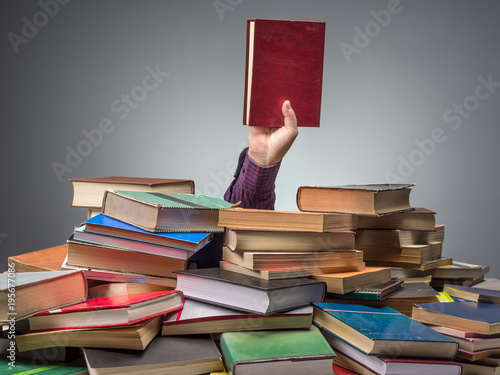 Man with book found among pile of books photo