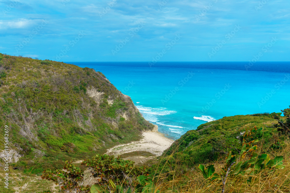 hidden picturesque Caribbean Bay, azure sea and green cliffs