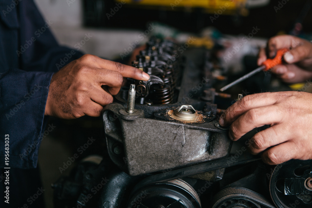 Mechanic fixing an engine for a head gasket repair in a garage. Mechanic fixing an engine for a head gasket repair in a garage.