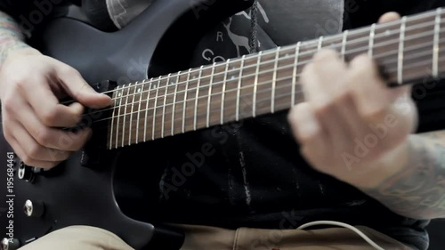a man with tattoos on his hands playing an electric guitar in a music store.