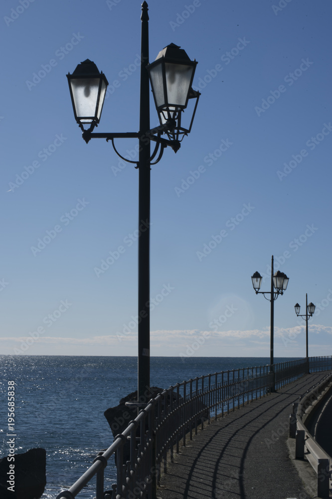 Wrought Iron Lamp Posts Line the Walkway on the Edge of the Sea