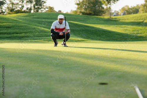 man on a golf course lining up his putt