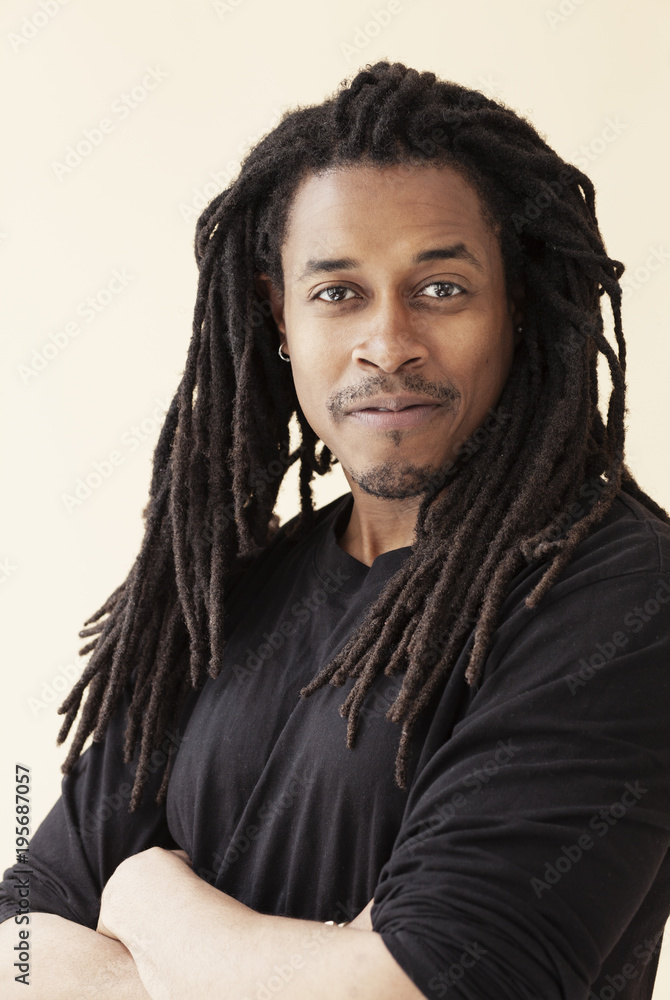 Portrait of confident black man on beige background with arms crossed.