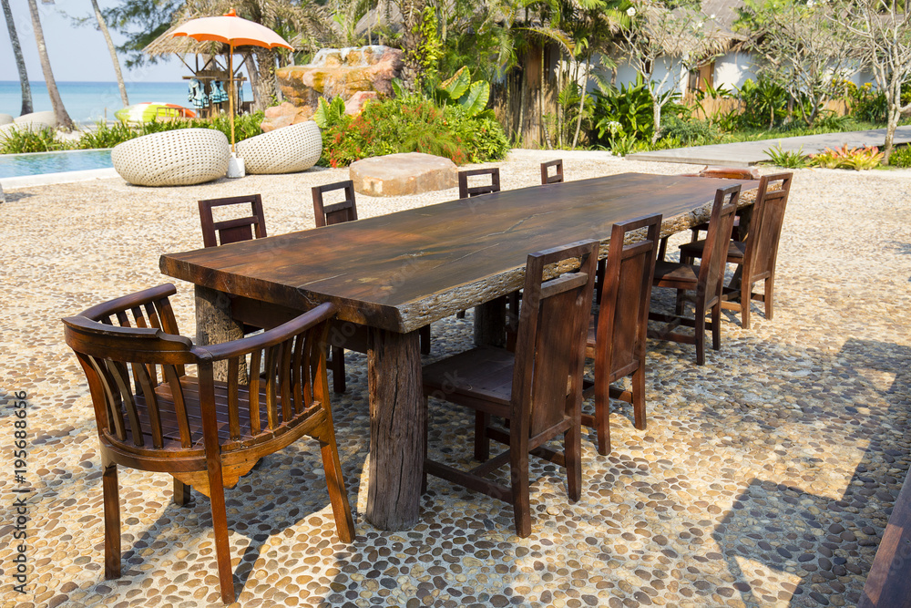 Table and wooden chairs in tropical beach next to the sea water, Thailand. Close up
