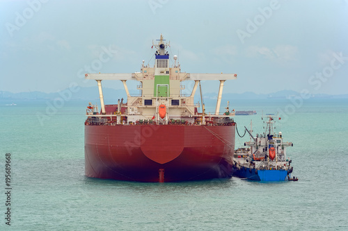 Loading anchored oil supertanker via a ship-to-ship oil transfer (STS) from raid tanker