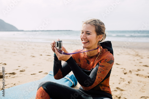 Woman in wetsuit taking a photo with action camera photo
