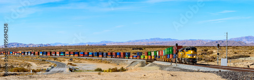 Photo Wide panorama of Union Pacific railroad locomotive carrying long freight cars