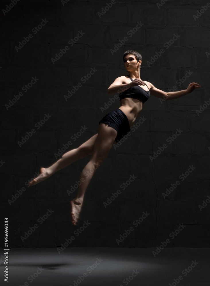 Ballet dancer in top and shorts view in dark room