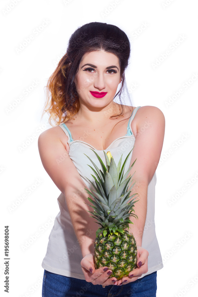 Summer studio portrait of a beautiful young brunette woman with long hair. A girl in a summer T-shirt and jeans is holding a pineapple in her hands. Concept: summer photography and a sunny mood Summer studio portrait of a beautiful young brunette woman with long hair. A girl in a summer T-shirt and jeans is holding a pineapple in her hands. Concept: summer photography and a sunny mood