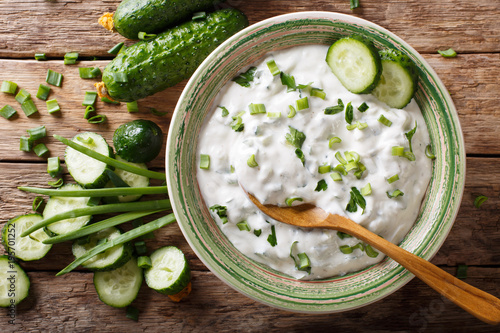 sauce of yogurt with herbs, spices and cucumber close-up on the table. raita. Horizontal top view