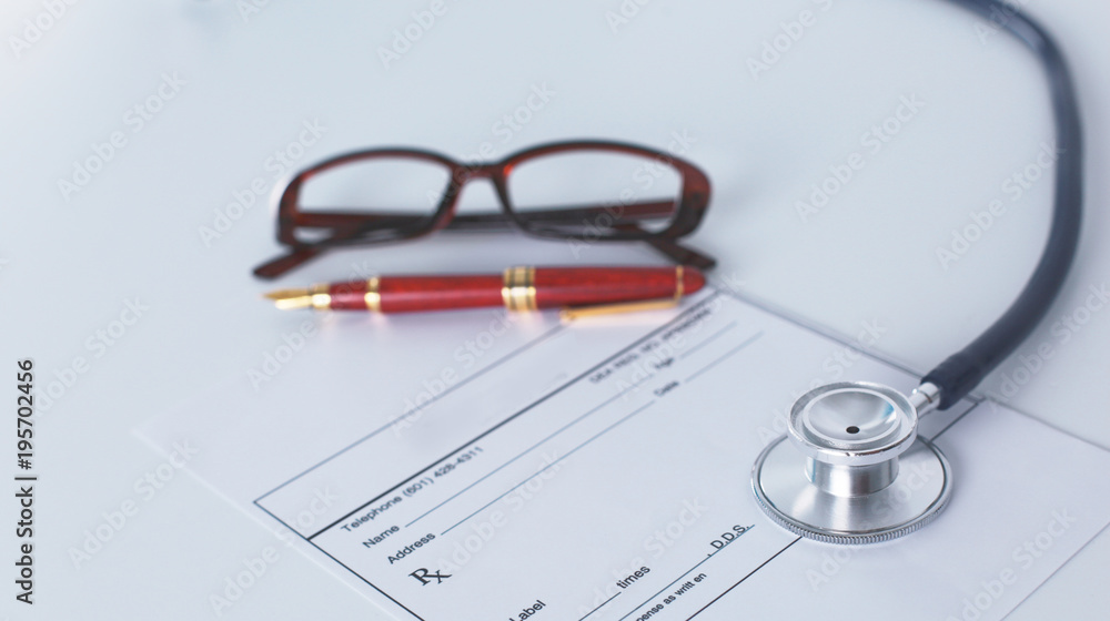 Doctor's workspace working table with patient's discharge blank paper form, medical prescription, stethoscope on desk Doctor's workspace working table with patient's discharge blank paper form, medical prescription, stethoscope on desk