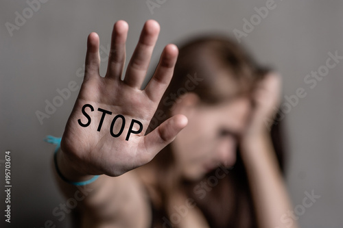Sad teenage girl shows the inscription "stop" on the palm