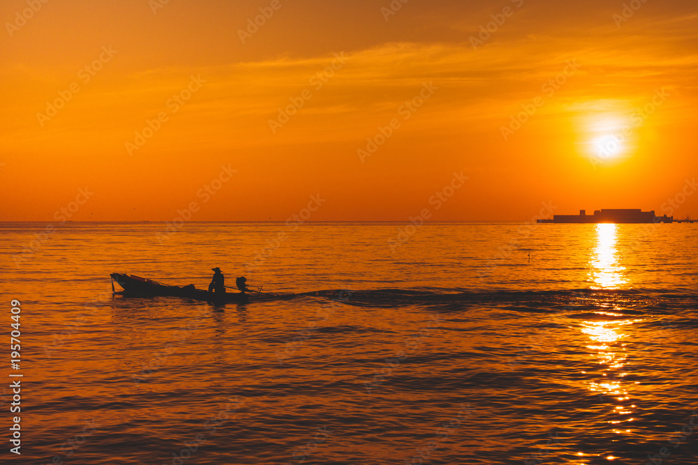 Silhouette of fishing boat and fisherman on sunset.