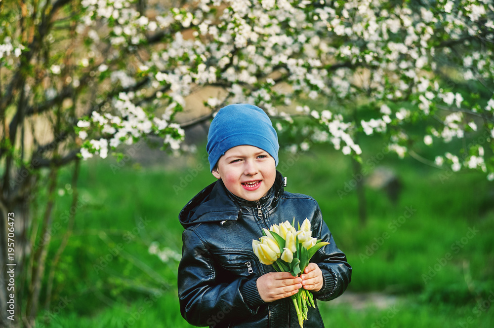 Boy in the spring flowering garden with a bouquet of flowers in his hands