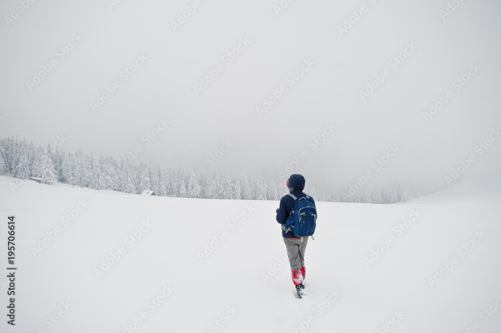 Man tourist photographer with backpack, at mountain with pine trees covered by snow. Beautiful winter landscapes. Frost nature.