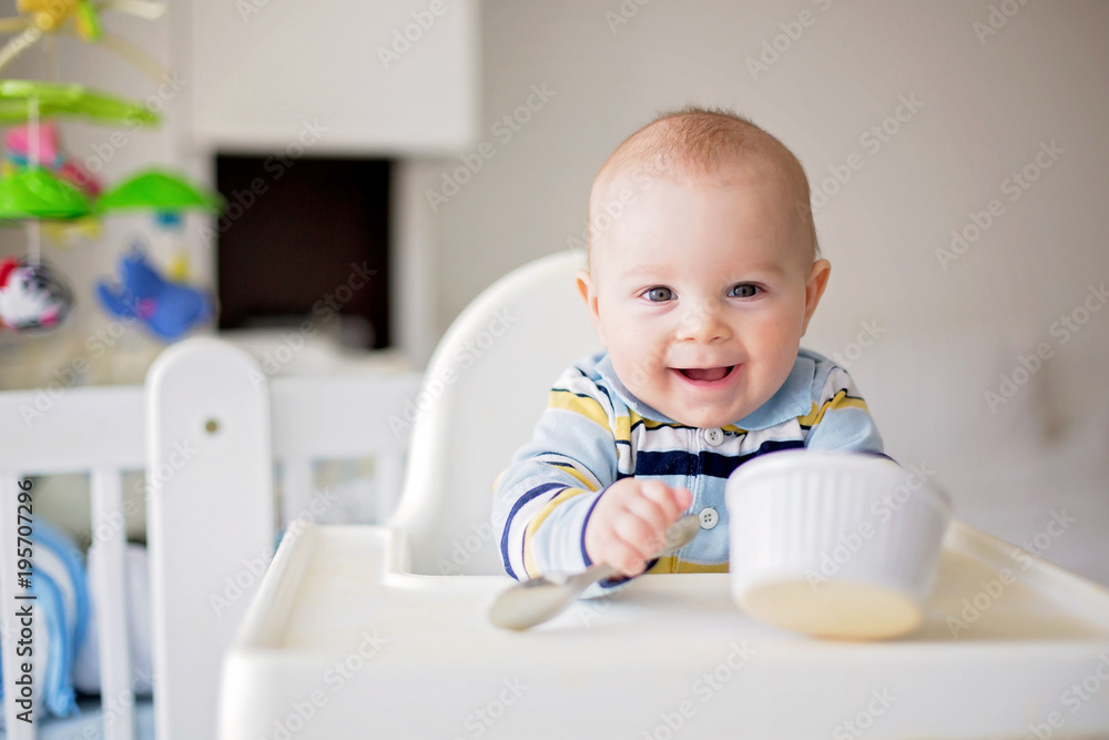Cute little baby boy, eating mashed vegetables for lunch, mom feeding him Cute little baby boy, eating mashed vegetables for lunch, mom feeding him