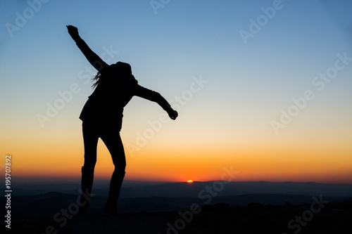 A young woman shows joyous gestures and dances in the setting sun of Dartmoor, United Kingdom.