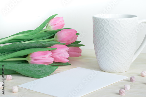 Fototapeta Naklejka Na Ścianę i Meble -  Soft feminine desktop with pink tulips, designer mug and postcard
