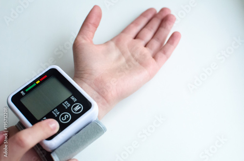 closeup of a young a patient woman at the doctors office whose blood pressure is being measured with a sphygmomanometer, which shows a high blood pressure